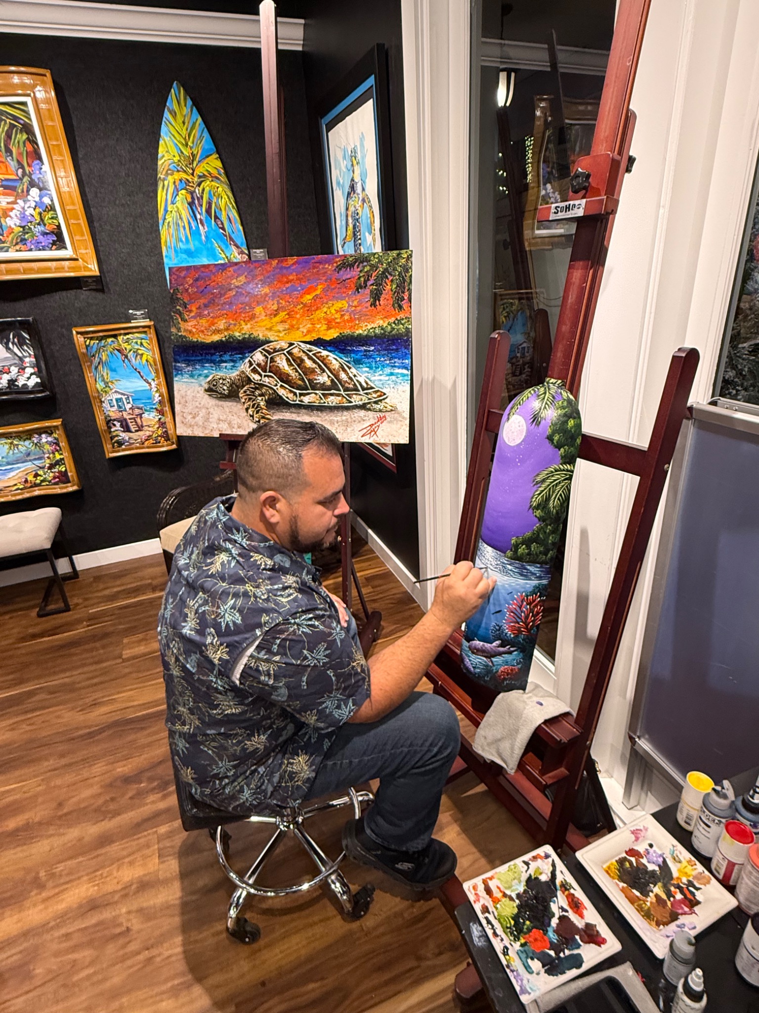 Danilo painting in his studio surrounded by colorful artwork